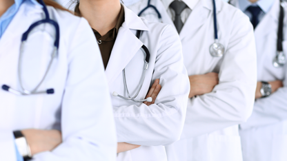 Gruppo di medici in camice bianco dei quali si vede solo il busto, con stetoscopi in posa uno accanto all’altro con le braccia conserte